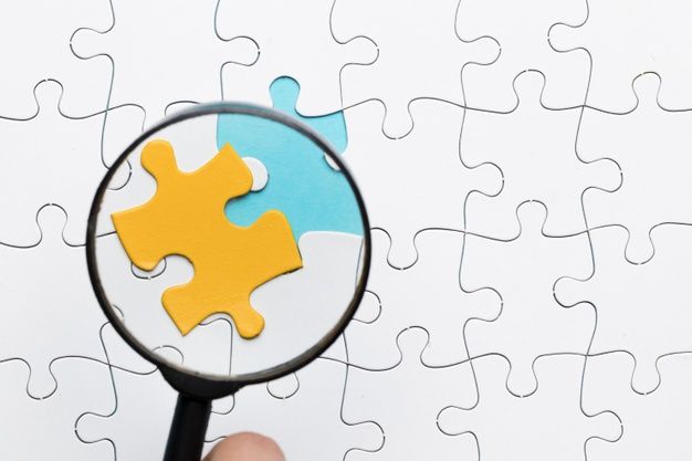 Magnifying glass focusing on yellow puzzle piece over white puzzle piece background | Premium Photo