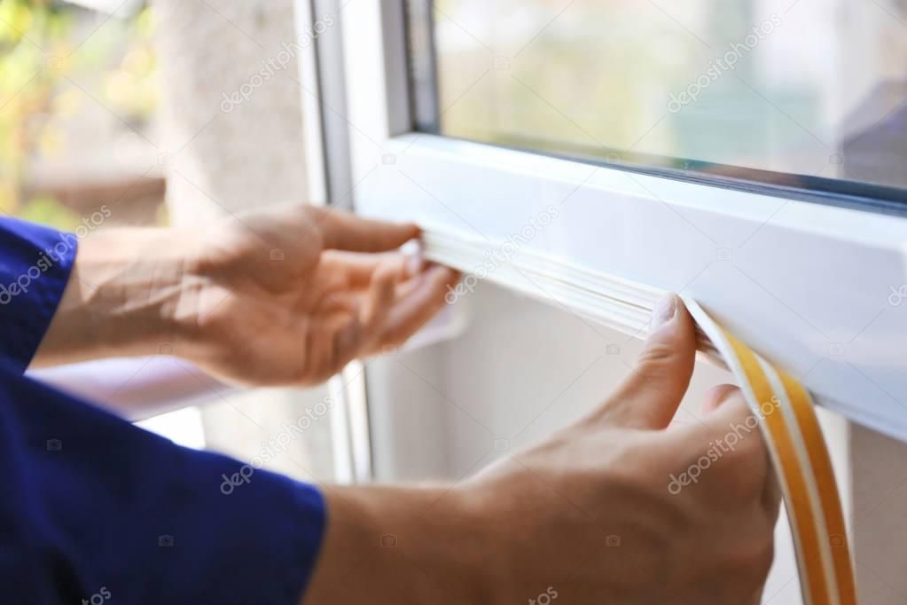 Worker putting sealing foam tape on window