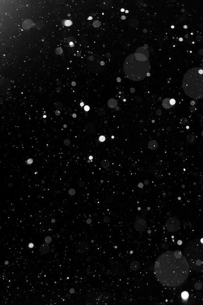 A bokeh of white snow on a black background | Premium Photo